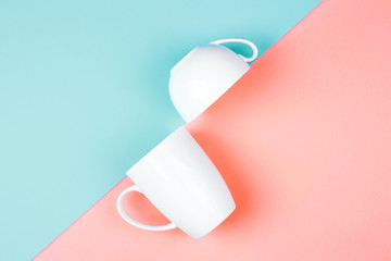 Two white cups on color background. Abstract, top view. Living coral and Limpet shell. Trendy colors of the 2019.