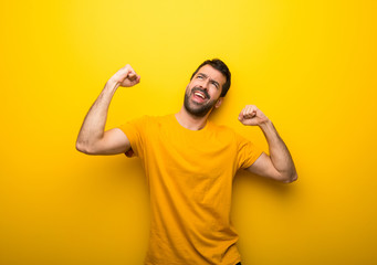 Fototapeta premium Man on isolated vibrant yellow color celebrating a victory in winner position