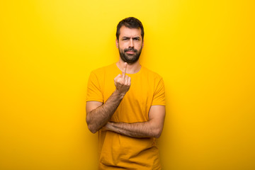 Obraz premium Man on isolated vibrant yellow color making horn gesture