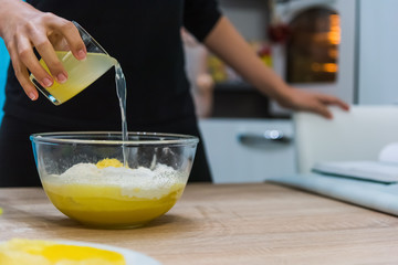 Woman pouring lemon juice in a cake dough