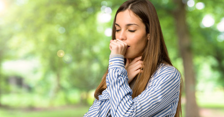 Young girl with striped shirt is suffering with cough and feeling bad at outdoors - obrazy, fototapety, plakaty