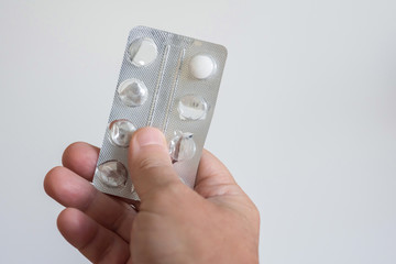 A hand holding a pack of medical pills at the white background. The notion of health.