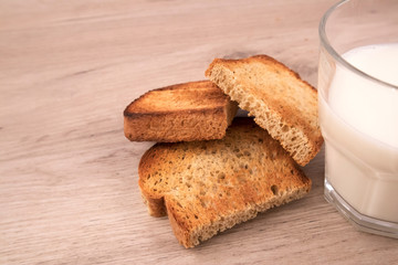 Toasted bread slices with appetite crispy crust and the glass of fresh milk on wooden board