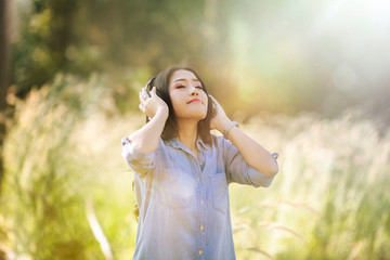 Woman relax by listening music with headphone in the nature green park, girl happy. Lifestyle Concept