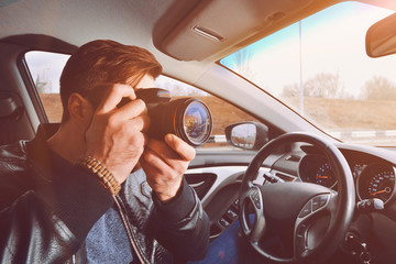 A man is taking pictures from a car window. Photographer traveler. The work of a private detective.