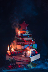 Christmas tree made out of books with candles and mysterious smoke. Winter decorations for readers...