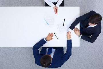 Group of business people and lawyer discussing contract papers sitting at the table, view from above. Businessmen shaking hands after agreement done