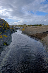 water puddle among rocks leads into the sea