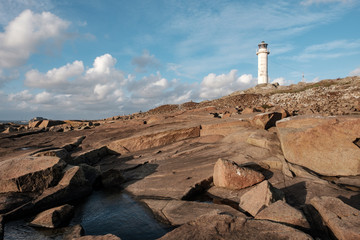 white lighthouse in the evening light up on the rocks