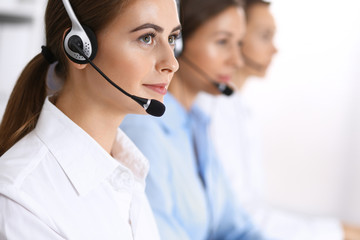 Call center. Group of operators at work. Focus at beautiful business woman in headset