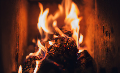 Burning logs and coal in fireplace. Warm  fire burning in dark furnace. Burning  pieces of wood in...