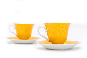 Two yellow cups of tea on whtie background. Isolated on white