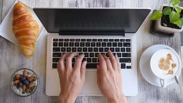 Overhead Of Modern Young Woman Working On Laptop With Coffee And