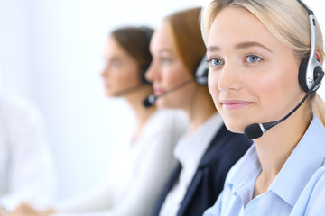 Call center. Group of operators at work. Focus at blonde business woman in headset