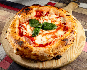 Italian Pizza in chopping board on a wooden table
