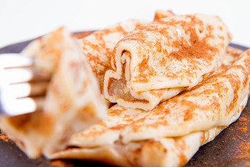 Pancakes stuffed with braised apples sprinkled with cinnamon eaten with a fork