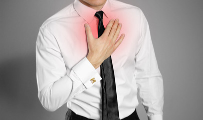 Businessman in a white shirt and tie holding his chest. Chest pain. Heartburn. Isolated background