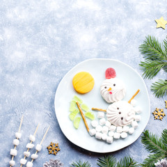 Christmas Snowman made of marshmallow and fruit jelly on a plate with fir branches and decorations. Top view, copy space
