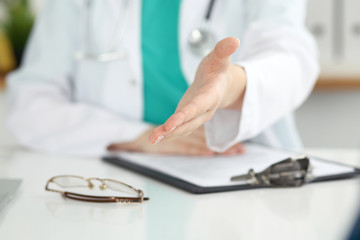 Female medicine doctor offering helping hand in office closeup. Physician ready to examine and save patient. Friendly and cheerful gesture