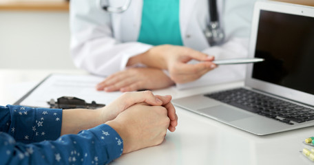 Close-up of a doctor and  patient  sitting at the desk while physician pointing into laptop computer. Medicine and health care concept