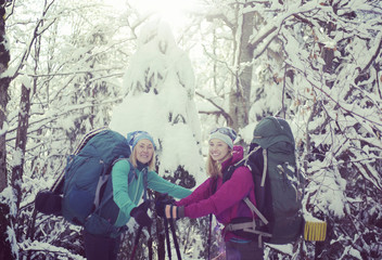 Two girls are walking in the winter forest.