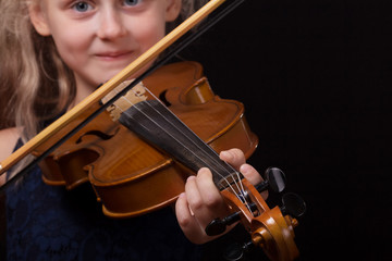 Happy little girl playing on violin on dark background © laboko
