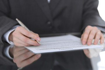 Fototapeta premium Close-up of female hands with pen over document, business concept. Lawyer or business woman at work in office
