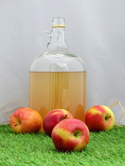 Glass Flagon of Cloudy Cider and Apples on Grass