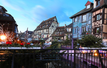 Traditional Alsatian half-timbered houses in old town of Colmar and branches of Christmas tree in the foreground.