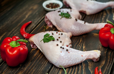 chicken legs with red pepper, tomatoes, parsley on a wooden background