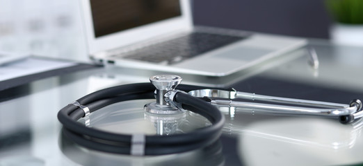 Stethoscope, prescription medical form lying on glass table with laptop computer. Medicine or pharmacy concept. Medical tools at doctor working table