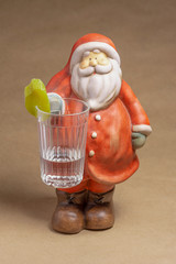 Clay figure of Santa Claus with a glass of vodka and pickled cucumber offers to sober