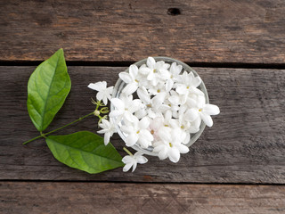 Jasmine floating in clear glass  on wooden background.