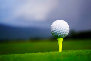 Golf ball on tee in beautiful golf course at sunset background. Golf ball on green in golf course at Thailand