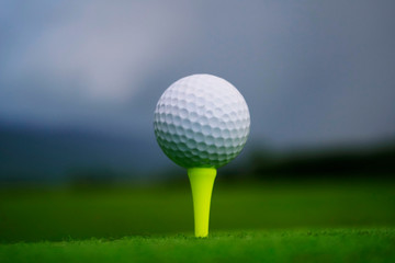 Golf ball on tee in beautiful golf course at sunset background. Golf ball on green in golf course at Thailand