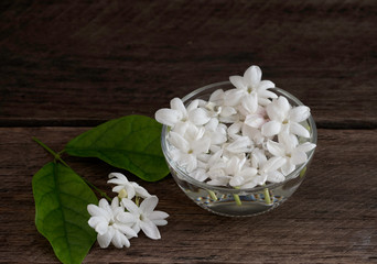 Jasmine floating in clear glass  on wooden background.