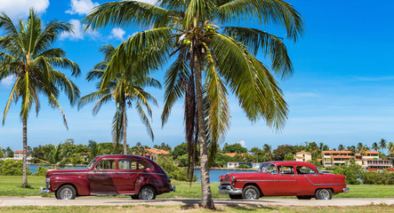 Amerikanischer roter und braun-roter Oldtimer parken am Strand unter Palmen in Havanna Kuba - Serie Kuba Reportage