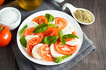 Close-up photo of caprese salad with ripe tomatoes, basil, buffalo mozzarella cheese. Italian and Mediterranean food concept. Fresh and healthy organic meal. Starter and antipasti. 