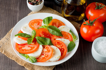Close-up photo of caprese salad with ripe tomatoes, basil, buffalo mozzarella cheese. Italian and Mediterranean food concept. Fresh and healthy organic meal. Starter and antipasti. 