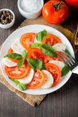 Close-up photo of caprese salad with ripe tomatoes, basil, buffalo mozzarella cheese. Italian and Mediterranean food concept. Fresh and healthy organic meal. Starter and antipasti. 