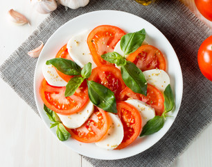 Close-up photo of caprese salad with ripe tomatoes, basil, buffalo mozzarella cheese. Italian and Mediterranean food concept. Fresh and healthy organic meal. Starter and antipasti. 
