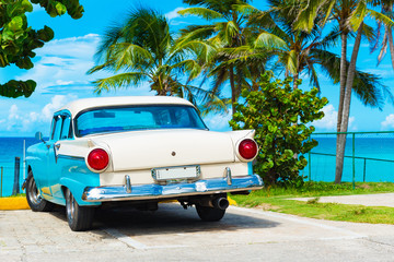 Amerikanischer Oldtimer parkt am Strand von Havanna unter Palmen in Kuba - Serie Kuba Reportage