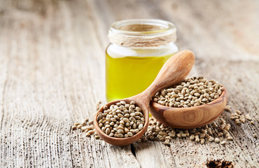Hemp oil and seeds on wooden background
