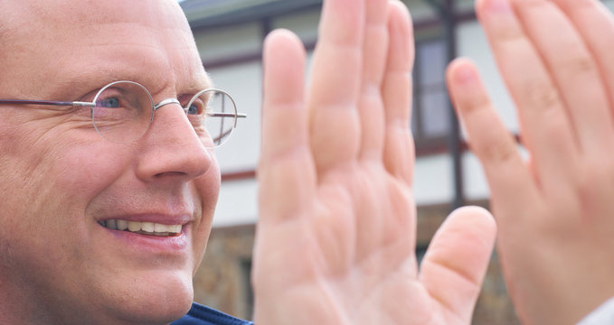 Father and daughter playing patty cake outdoors.