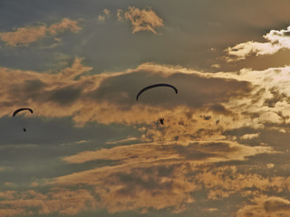 Paratroopers on motorized steamplanes fly against the blue sky with clouds