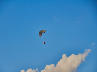 Paratroopers on motorized steamplanes fly against the blue sky with clouds