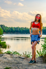 young girl in a jeans dress near forest lake in sunset