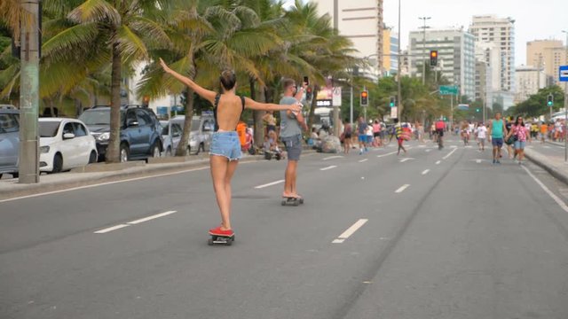 Skaters along on main street by famous Ipanema Beach in Rio de Janeiro Slow motion