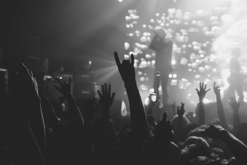 Hands of a crowd raised up at the music show to the singer on stage. Black and white. Black and...