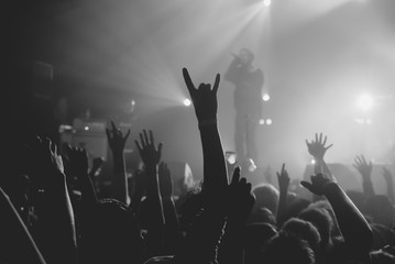 Hands of a crowd raised up at the music show to the singer on stage. Black and white. Black and white